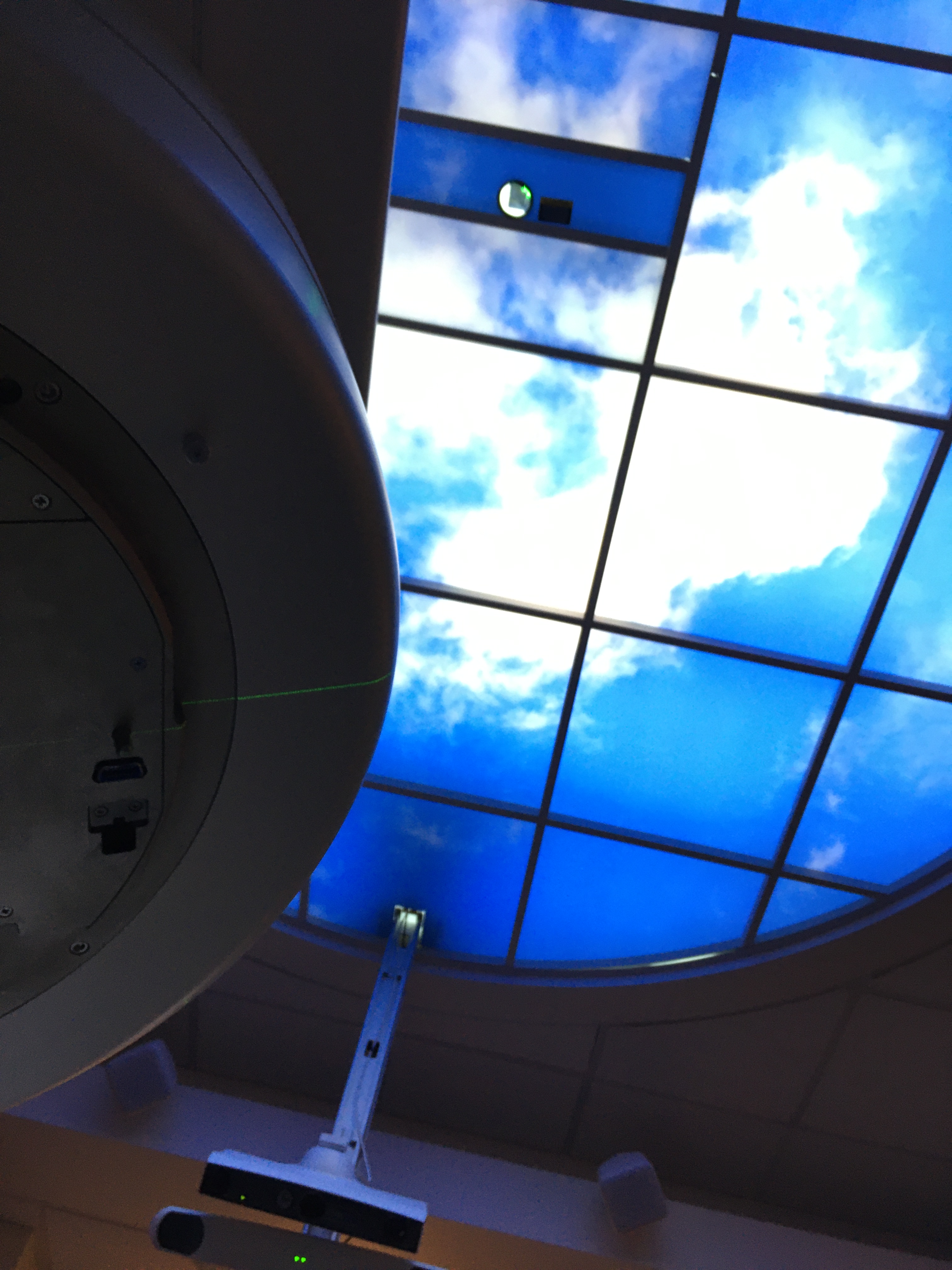 Photo of part of the radiation machine on the left, and the blue ceiling light above. It's an odd angle, taken from the view when inside the radiation machine.